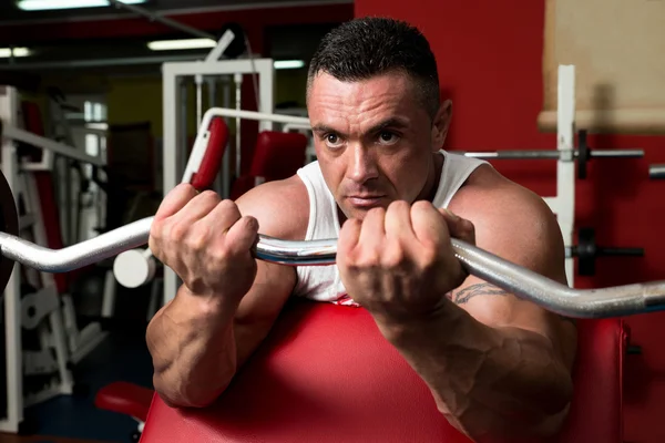 Mann im Fitnessstudio trainiert Bizeps mit Langhantel — Stockfoto