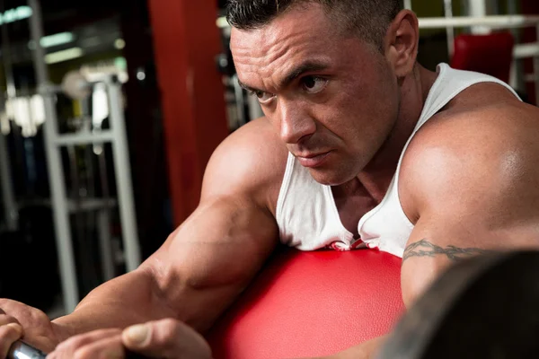 Hombre en el gimnasio ejercitando bíceps con barra — Foto de Stock