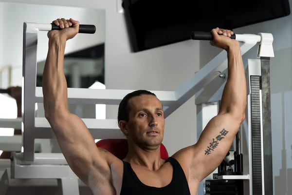 Aantrekkelijke man schouder pers doen met machine — Stockfoto