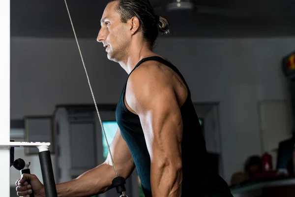 Hombre guapo haciendo ejercicios de tríceps con polea en el gimnasio — Foto de Stock