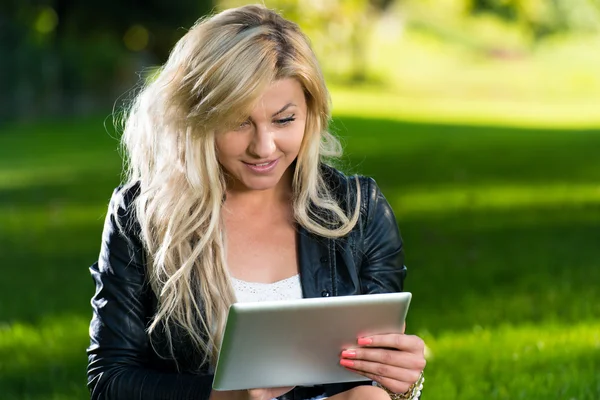 Parkta dijital tablet kullanan genç bir kadın. — Stok fotoğraf