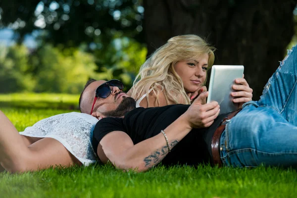 Jeune couple utilisant une tablette numérique dans le parc — Photo