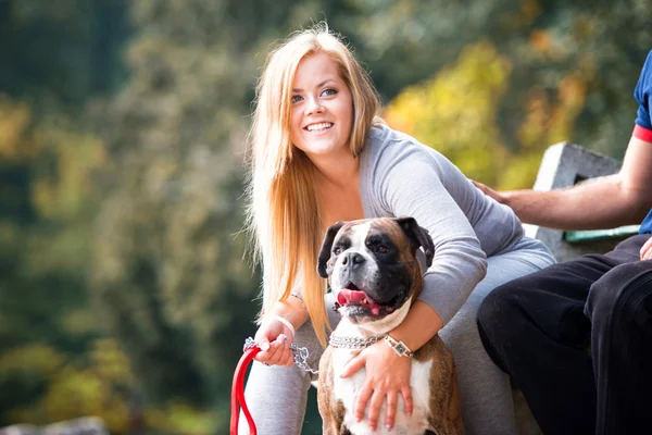 Пара сидящих на улице со своим домашним псом немецким боксером — стоковое фото