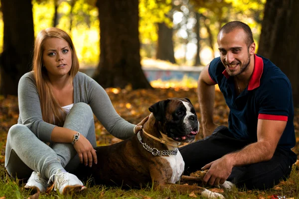 Пара сидящих на улице со своим домашним псом немецким боксером — стоковое фото