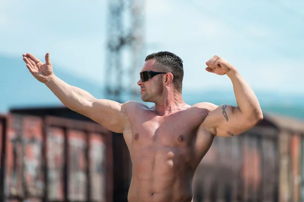 Bodybuilder posiert an der Eisenbahn — Stockfoto