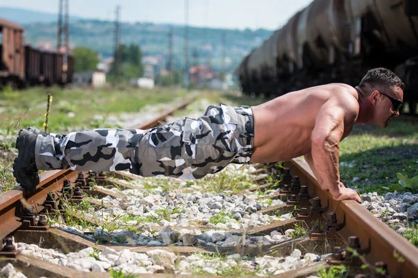 Man doen pushups aan spoorweg — Stockfoto