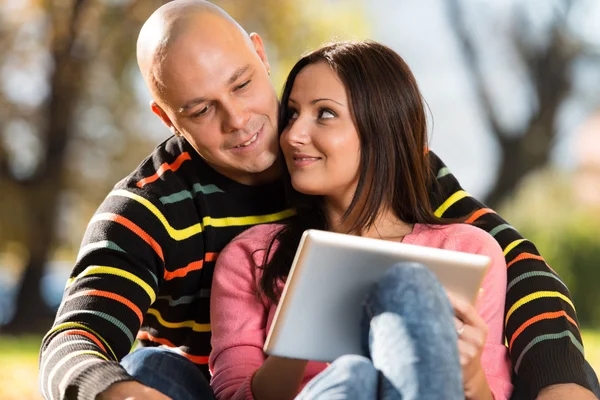 Male And Female Look At Electronic Tablet In Park — Stock Photo, Image