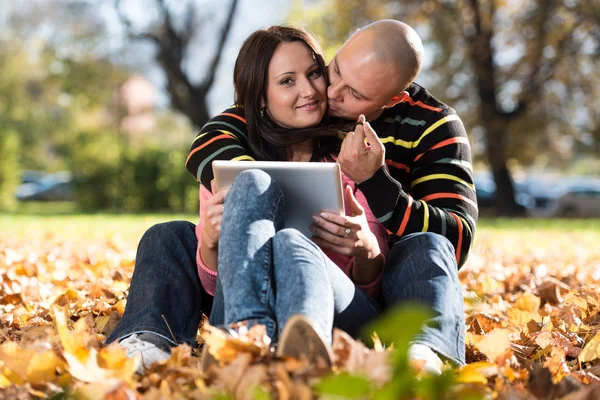 Glückliches junges Paar mit Tablet-Computer im Park — Stockfoto