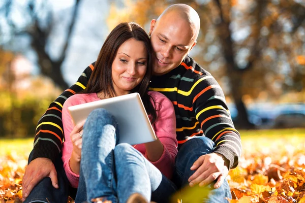 美丽的夫妇坐在公园里和使用平板电脑 — 图库照片