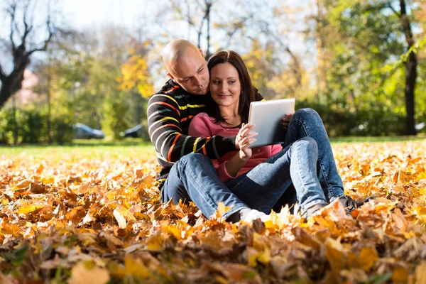 Beautiful Couple Sitting In Park And Using Tablet Computer — Stock Photo, Image