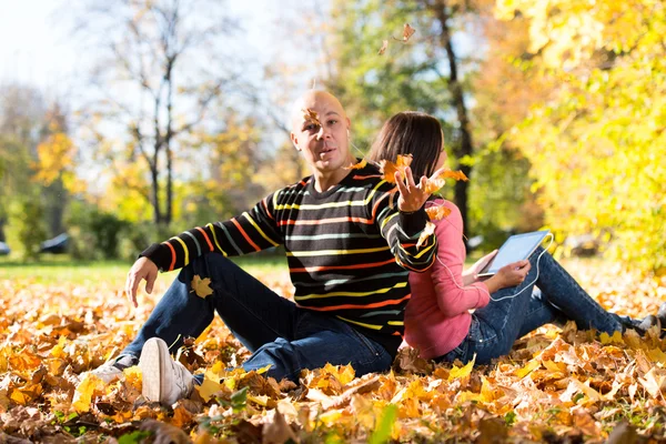 Couple écoutant de la musique et jetant des feuilles — Photo