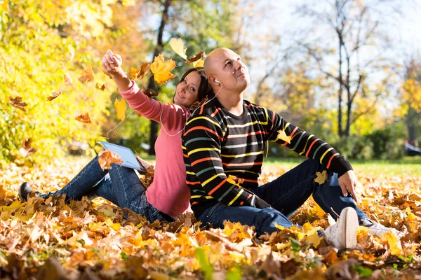 夫妇在秋天的落叶上听音乐 — 图库照片