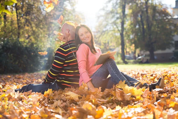 Couple écoutant de la musique et jetant des feuilles — Photo