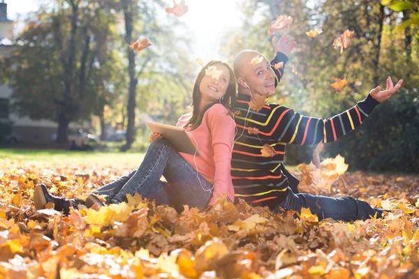 Pareja escuchando música en hojas de otoño —  Fotos de Stock