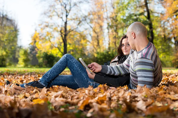 Glada unga par med tablet PC i parken — Stockfoto
