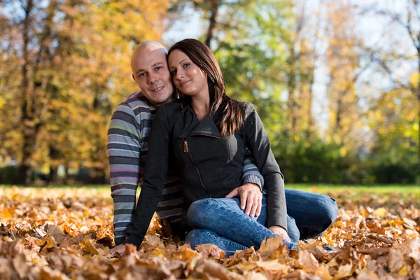 Пара, сидящая вместе в лесу осенью — стоковое фото