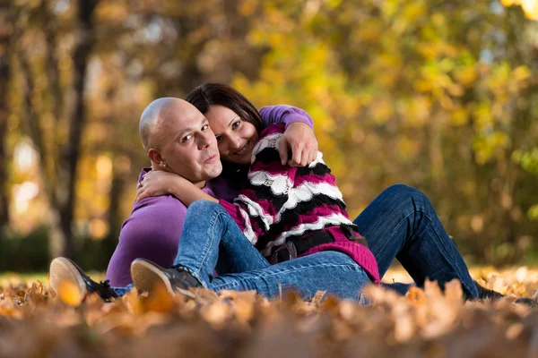 Счастливая пара, сидящая вместе в лесу осенью — стоковое фото