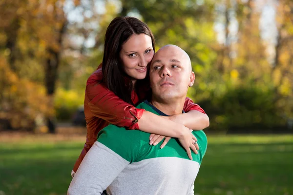 Homem carregando mulher piggyback no outono bosques — Fotografia de Stock