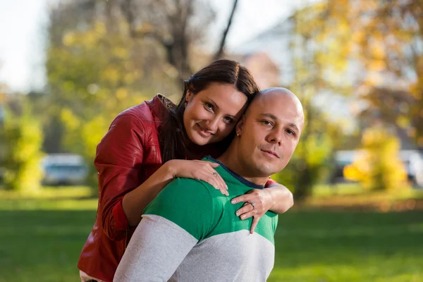 Macho llevando sonriente hembra en su espalda en parque — Foto de Stock