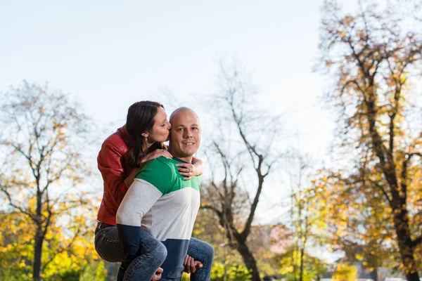 Male Carrying Smiling Female On His Back At Park