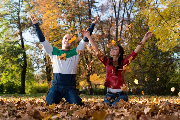 Pareja joven lanzando hojas de otoño —  Fotos de Stock