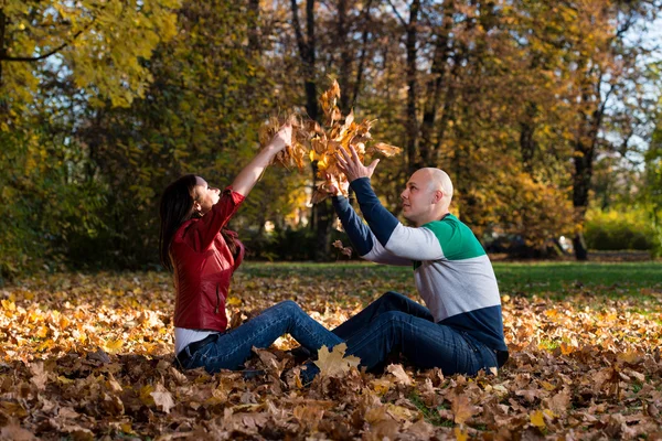 Couple s'amuser avec des feuilles d'automne dans le jardin — Photo