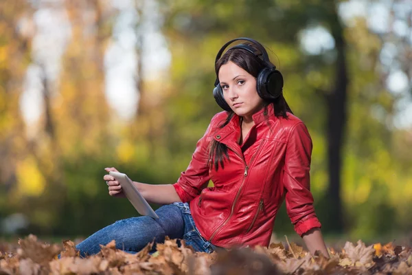 Flicka lyssnar musik i höst solen — Stockfoto