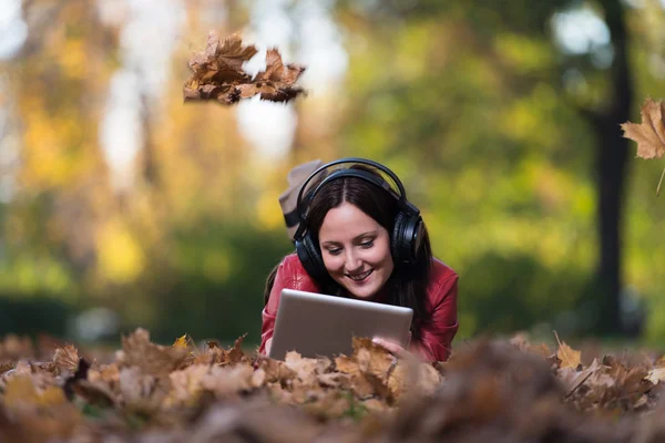 Flicka lyssnar musik i höst solen — Stockfoto