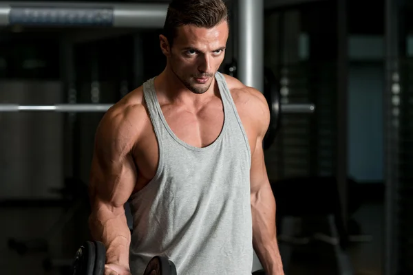 Człowiek na siłowni, ćwiczenia bicepsów z hantlami — Zdjęcie stockowe