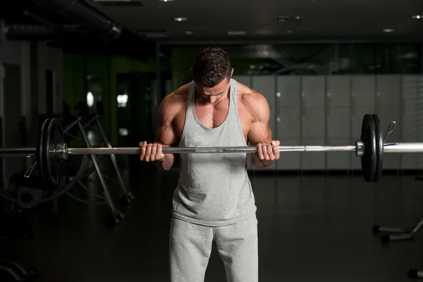 男人在健身房里锻炼肱二头肌与杠铃 — 图库照片