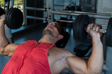 eğimli göğüs Pres jimnastik salonu içinde dumbbells ile yapan erkek