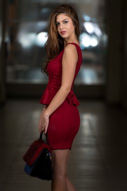 güzel model giyen bir kırmızı elbise ve deri çanta