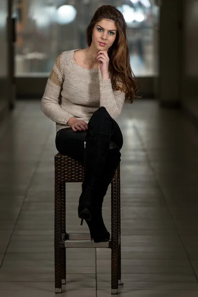 Güzel genç kahverengi model sandalyede oturuyor — Stok fotoğraf