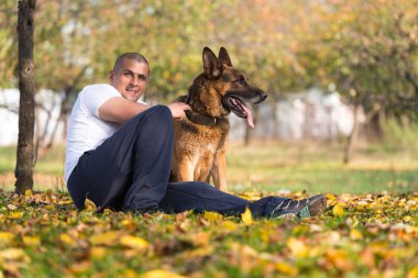 yetişkin adam açık havada onun Alman kurdu ile oturuyor