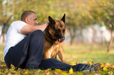 yetişkin adam açık havada onun Alman kurdu ile oturuyor