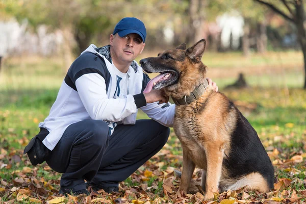 Dospělý muž sedí venku s jeho německého ovčáka — Stock fotografie