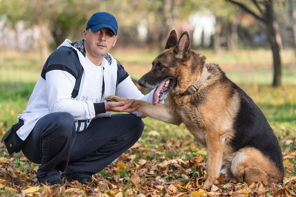 Homem segurando cão pastor alemão — Fotografia de Stock