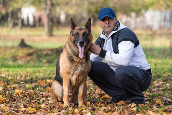 Homem segurando cão pastor alemão — Fotografia de Stock