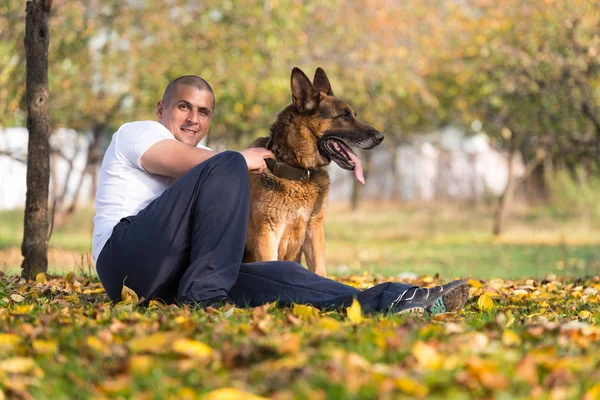Erwachsener Mann sitzt draußen mit seinem Schäferhund — Stockfoto
