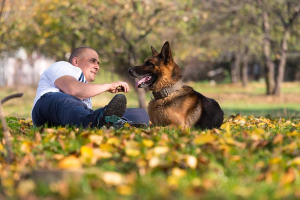 Homem segurando cão pastor alemão — Fotografia de Stock