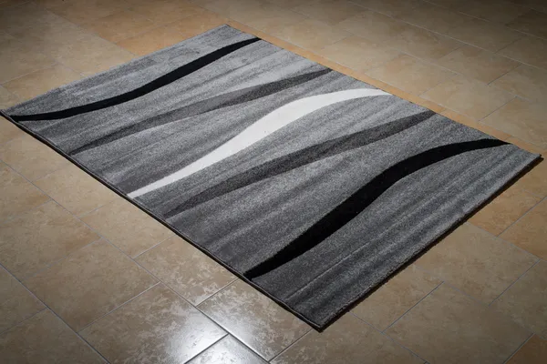 Черный ковер, лежащий на полу — стоковое фото