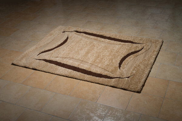 Один коричневый ковер, сложенный на полу
