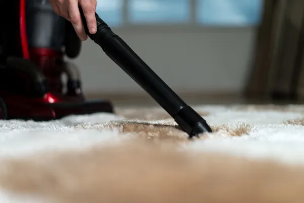 Mann reinigt Teppich mit Staubsauger — Stockfoto