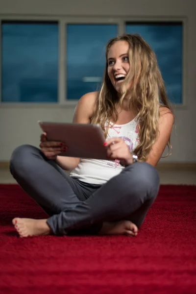 Ipad を使用してカーペットの上に立地しながら幸せな女 — ストック写真