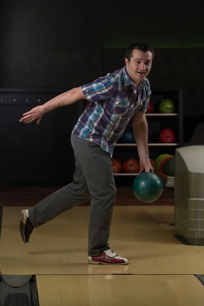 Leende ung man leker med ett bowlingklot — Stockfoto