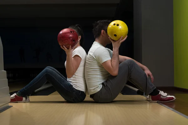 Genç bir çift yüzlerini bowling topun arkasında saklanıyor — Stok fotoğraf