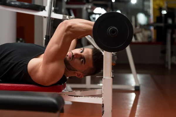 Hombre en el gimnasio haciendo ejercicio tríceps con barra —  Fotos de Stock