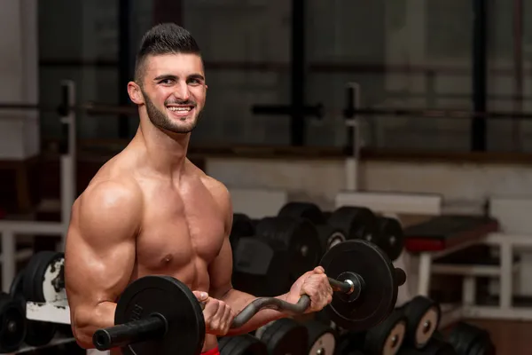 Män i gymmet utför biceps lockar med en skivstång — Stockfoto