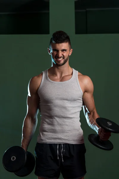 Homem muscular exercício bíceps com halteres — Fotografia de Stock