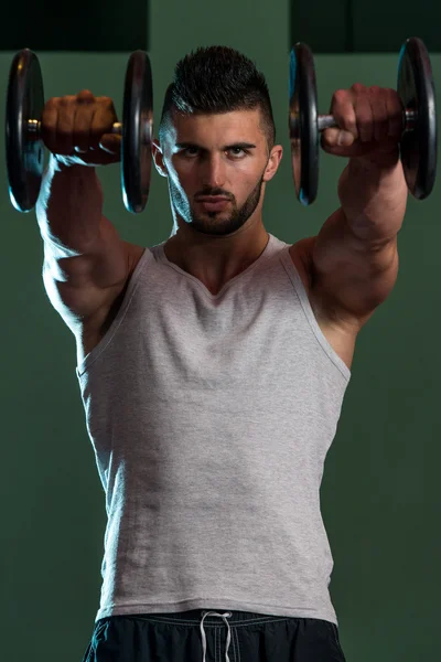 Мускулистые мужчины тренируют плечо с гантелями — стоковое фото